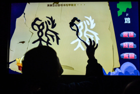 小观众正在多媒体展台上尝试书写“鸡”字的甲骨文_120684.jpg