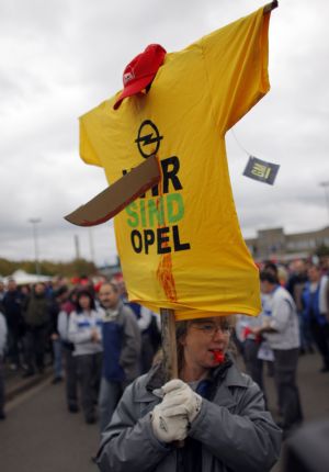 An employee of German car manufacturer Opel holds up a t-shirt reading 'We are Opel' punctured with a cardboard knife symbolizing GM, during a warning strike at the Opel plant in Kaiserslautern November 5, 2009. The board of General Motors Co has opted to keep Opel, undoing months of painstaking negotiations to sell the European unit to a Russian-backed group led by Canada's Magna. GM confirmed the decision made by its 13-member board after a meeting of directors on Tuesday in Detroit.