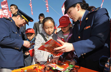 Officers from local commerce administration talk with students about food safety during an event to mark the World Consumer Rights Day in Yinchuan, Ningxia Hui Autonomous Region, March 15, 2009. Lots of such events were held across China on Sunday. (Xinhua/Wang Peng)