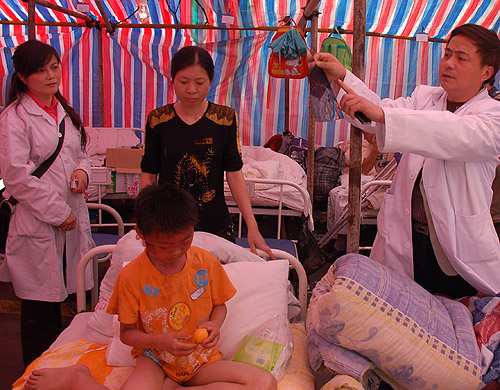 A doctor explains the nature of a boy’s wounds inside a makeshift hospital tent in Dujiangyan