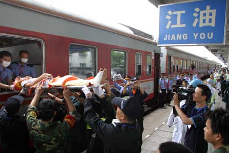 Rescuers carry an injured onto the train at the Jiangyou Railway Station in Jiangyou, southwest China's Sichuan Province, May 21, 2008. More than 300 people injured in the May 12 quake hitting Sichuan were transferred by a special train to Kunming, capital of southwest China's Yunnan Province, on May 21.